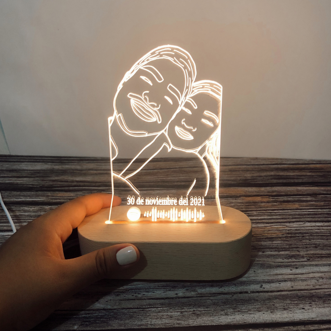 Mano sosteniendo lámpara personalizada de madera con foto de mamá e hija, fecha y código de canción, luz cálida